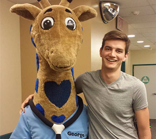 Niño adolescente con la jirafa George, la mascota