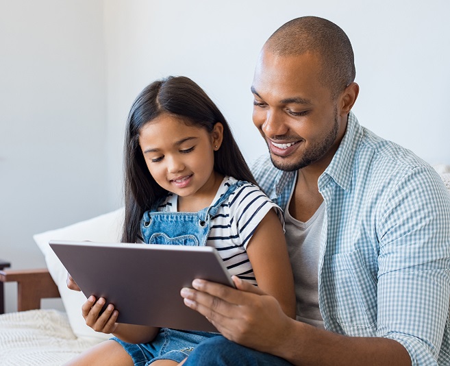 Foto de una niña con su padre mirando una tablet