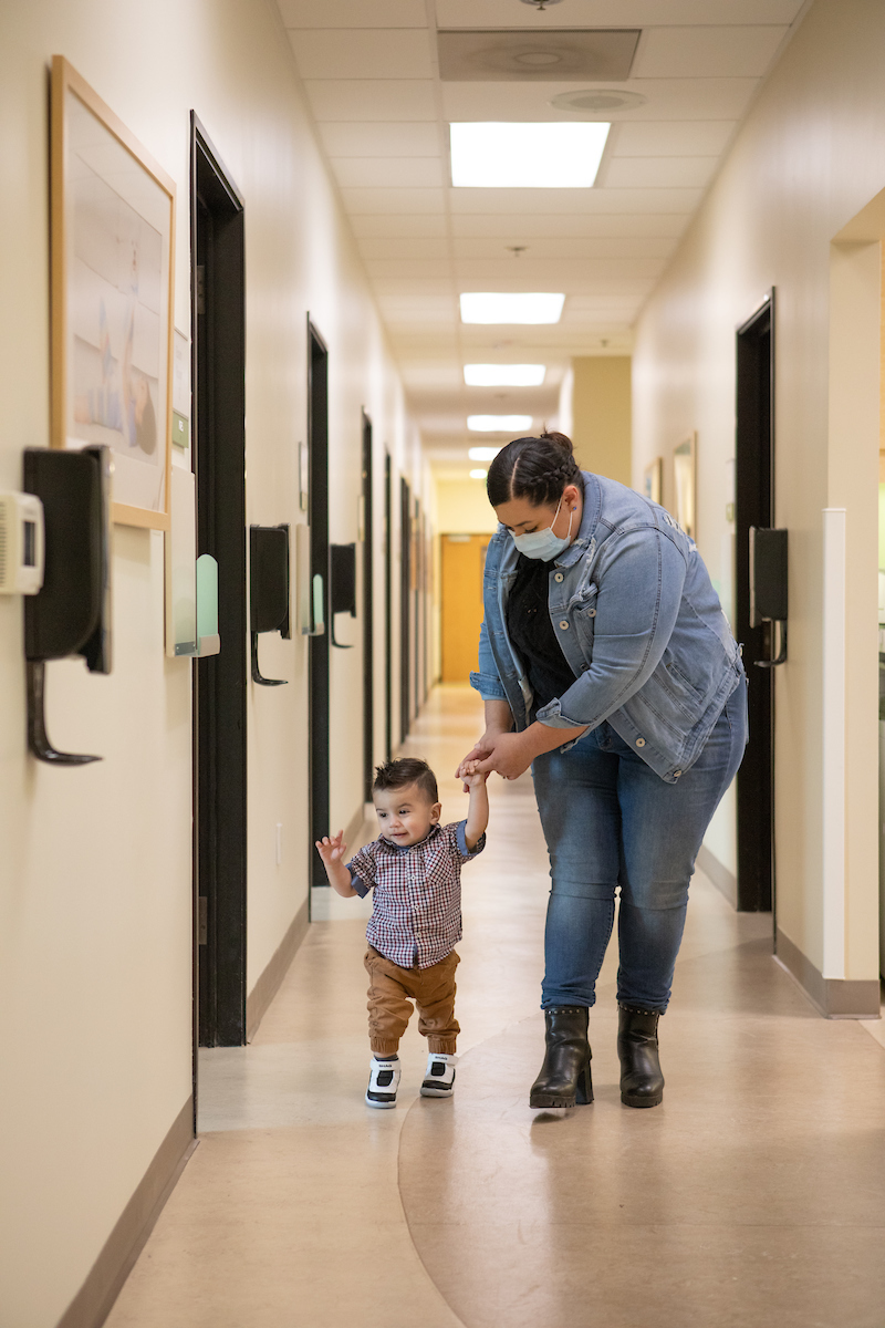 Fotografía de Rafael y su madre caminando en el pasillo de la clínica de Neurología