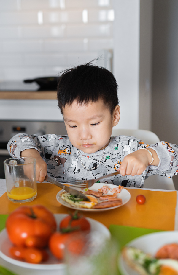 Foto de un niño sentado en la mesa de la cocina comiendo una comida saludable
