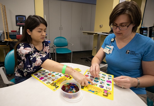 Photo of Valley Children's speech therapist sitting at table playing a game with a teenage girl
