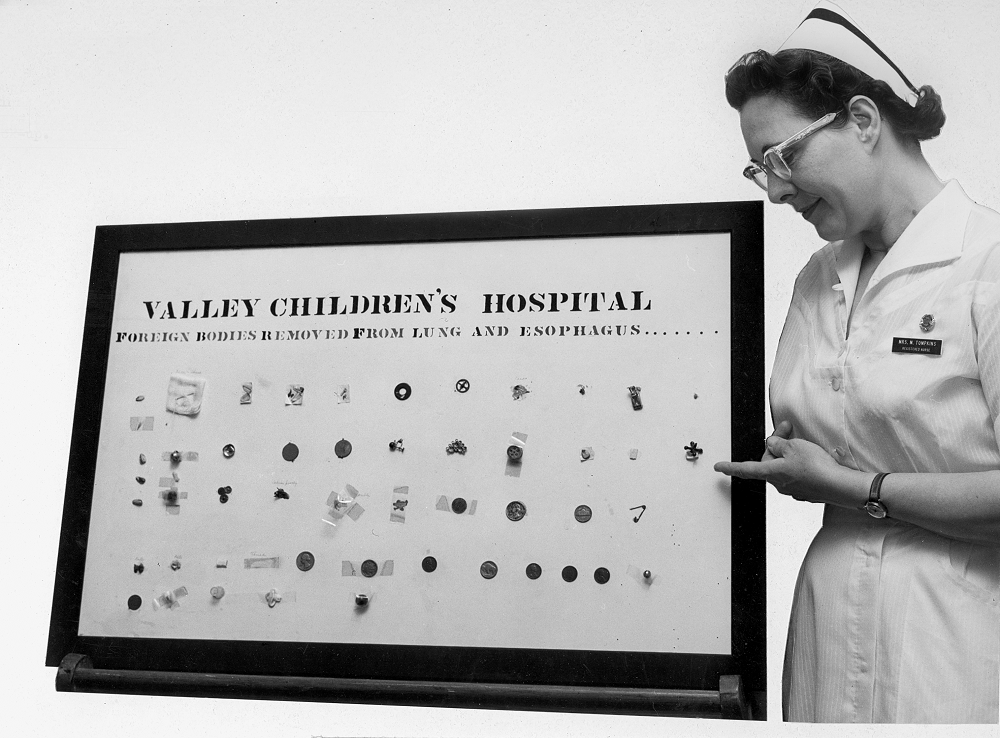 Una enfermera de <i>Valley Children's</i> señala el tablero de exhibición de objetos extraños extraídos del pulmón y el esófago