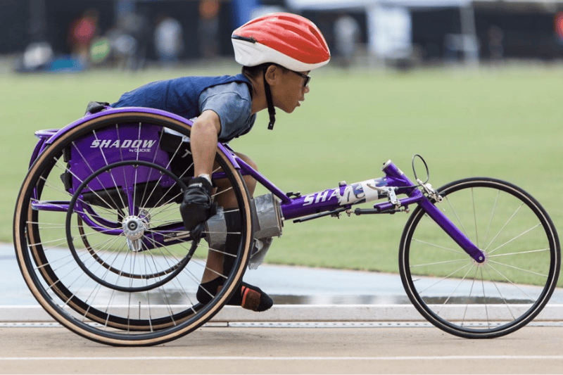 A child uses an adaptive track and field racing chair