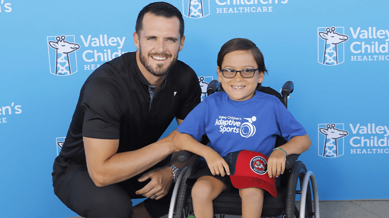 Derek Carr smiles next to Sylus, an Adaptive Sports athlete