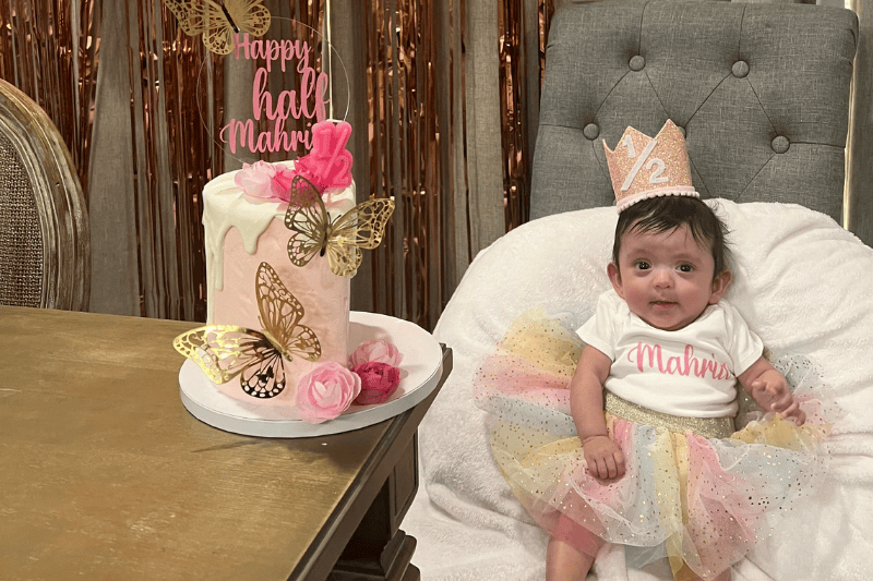 Una niña sonríe junto a su pastel de cumpleaños
