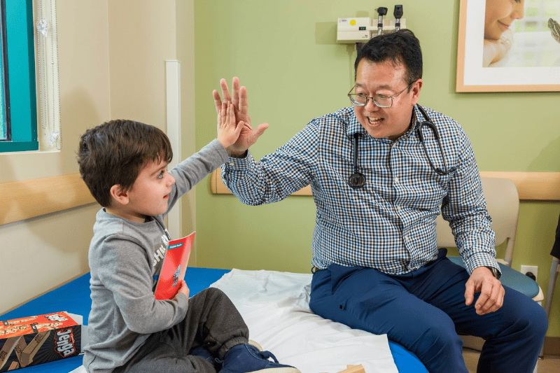 A doctor high-fives a young boy