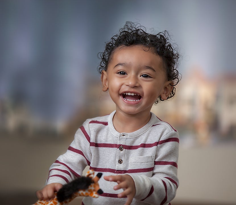 Un niño pequeño con cabello rizado sonríe
