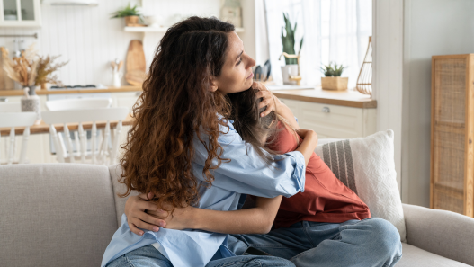 Mamá e hija abrazándose en el sofá