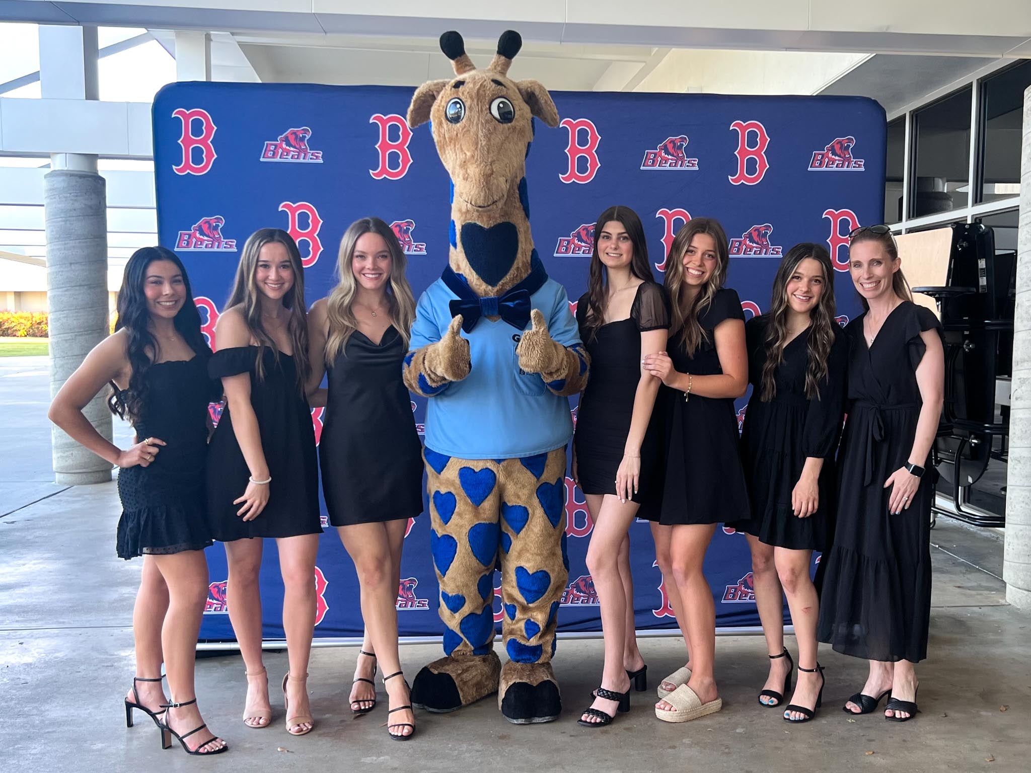 Girls wearing black formalwear in front of a backdrop