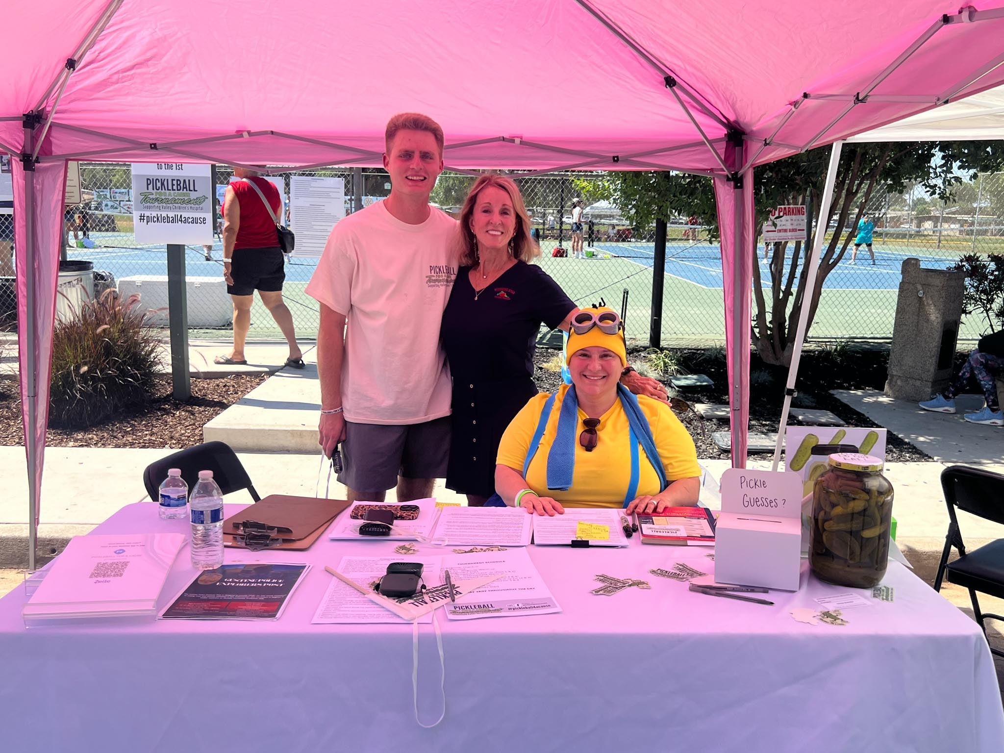 People smiling at a table under pink canopy