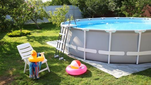 Above ground pool in backyard with pool toys surrounding it 