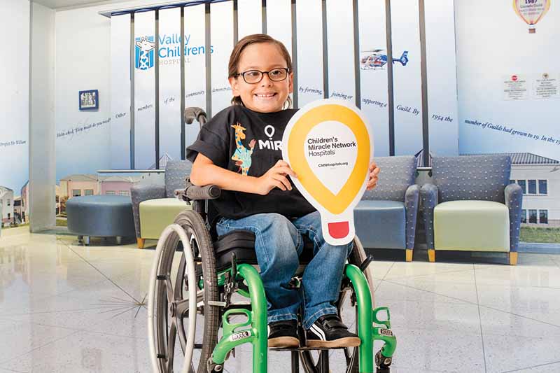Niño en silla de ruedas sostiene un globo de los Hospitales Children's Miracle