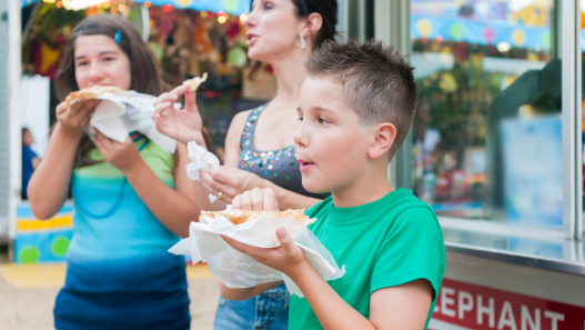 Child and adults eating food at a fair