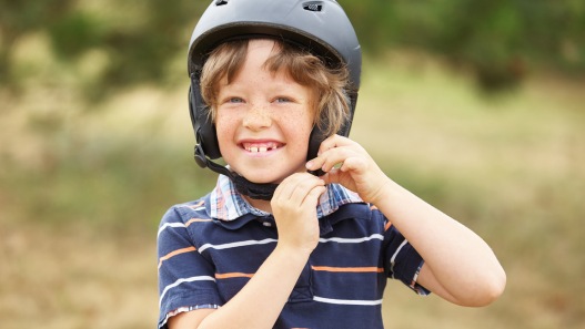 Child putting on a bike helmet