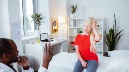Child holding their head at the doctor