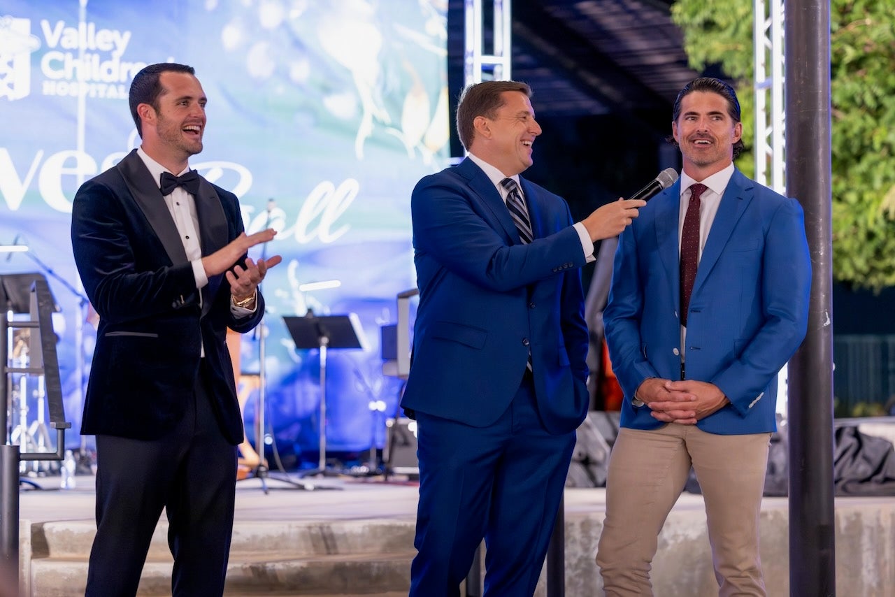 Tres hombres en el escenario sonriendo