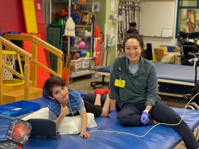 Un niño y un miembro del equipo de rehabilitación juegan en el gimnasio