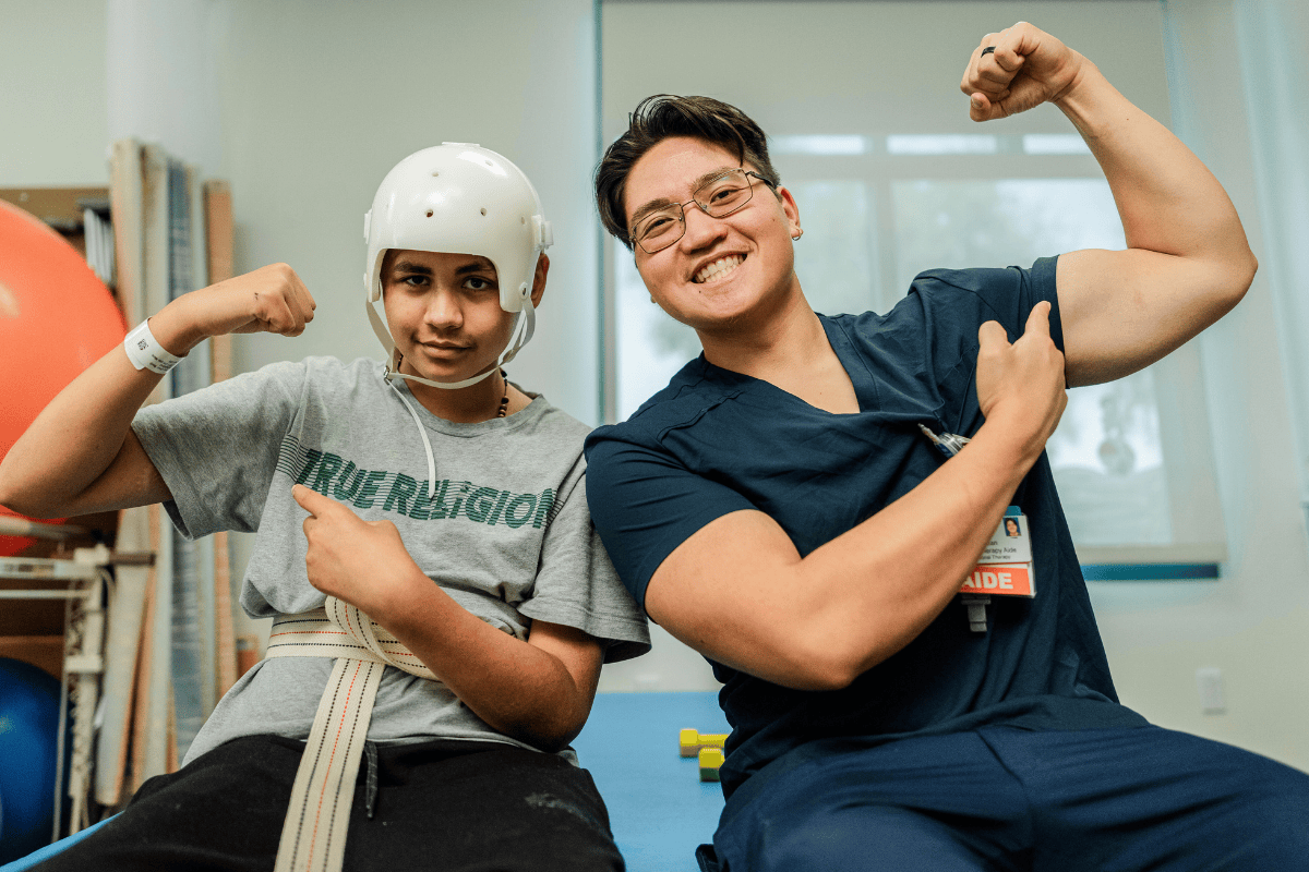 Un asistente del equipo de rehabilitación posa y sonríe con un paciente