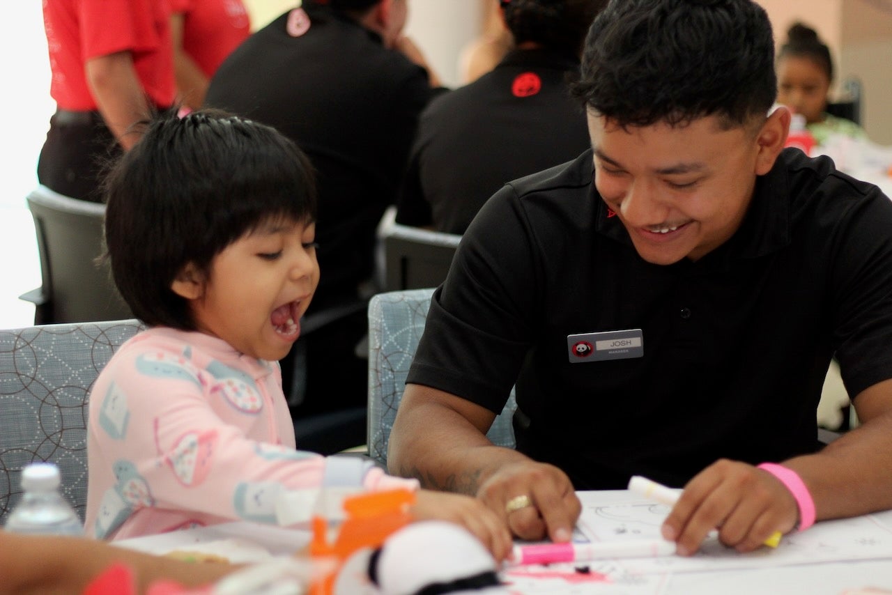 Un empleado de Panda Express colorea con un niño riendo