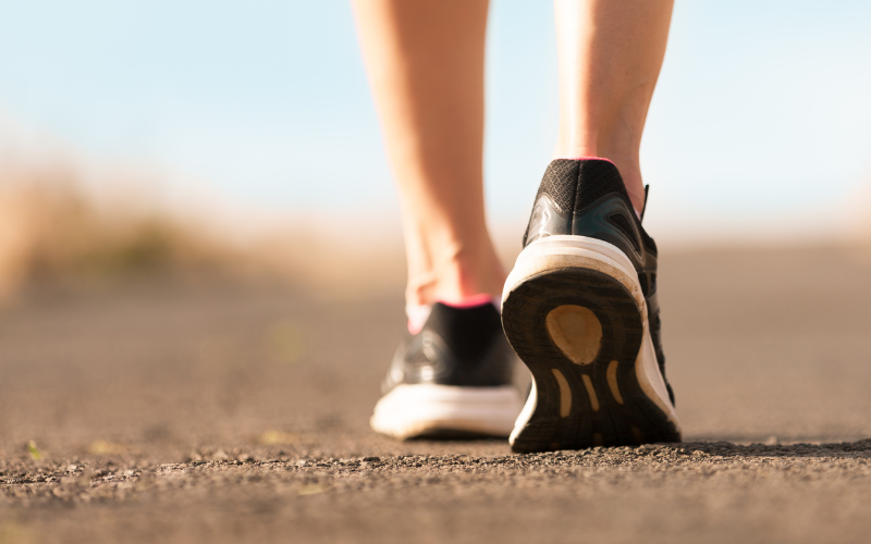 A person walks along a walking trail in athletic shoes