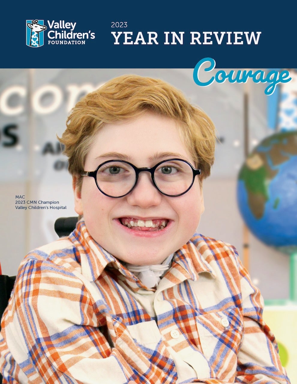 Mac, a child with glasses and plaid shirt, smiles