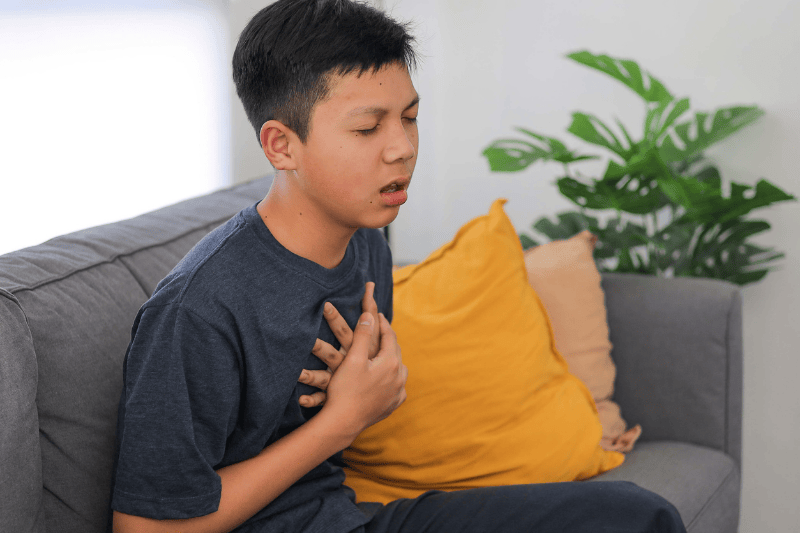 A teen boy puts his hands to his chest