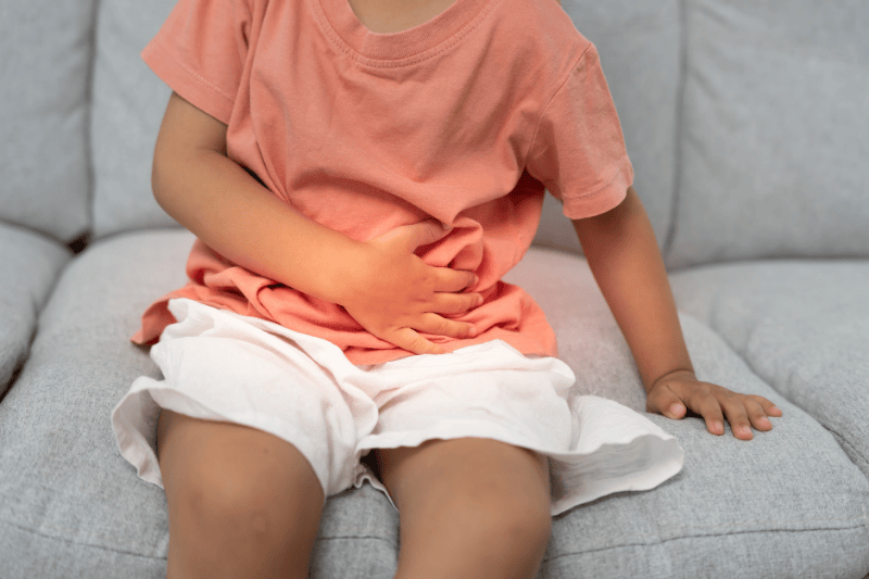 A young girl holds her stomach from a stomachache