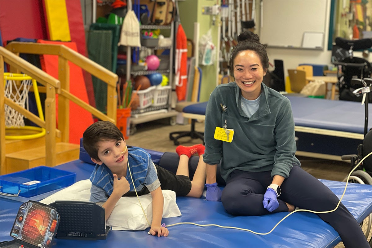 Un niño y un miembro del equipo de rehabilitación juegan en el gimnasio