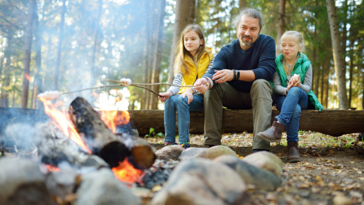 Dad and his daughters sitting safely around a campfire