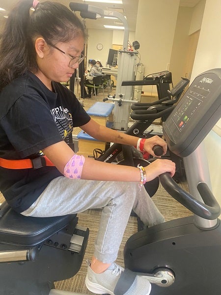 Faith rides a bicycle as part of her recovery