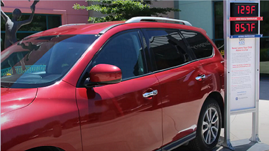 Vehículo utilitario rojo junto a un termómetro que muestra la temperatura exterior y la temperatura interior del vehículo