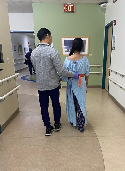 Faith walks down the hall with a Valley Children's Rehabilitation Center staff member