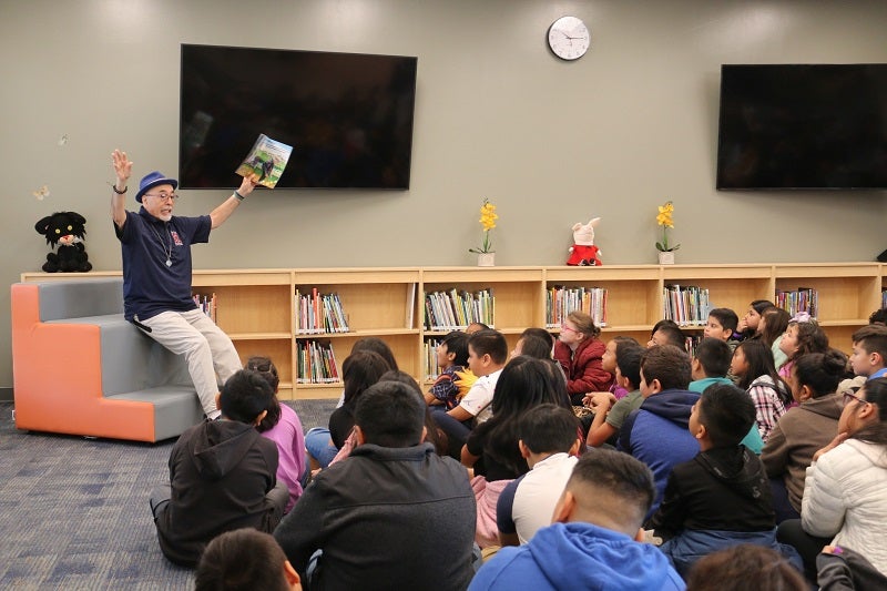Foto de Juan Filipe Herrera leyendo su libro a los niños de la escuela primaria Juan Filipe Herrera