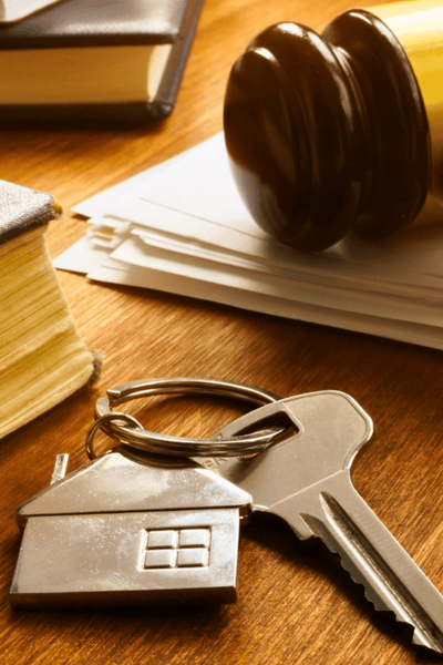 A set of keys sit on a desk next to legal books and a judge's gavel