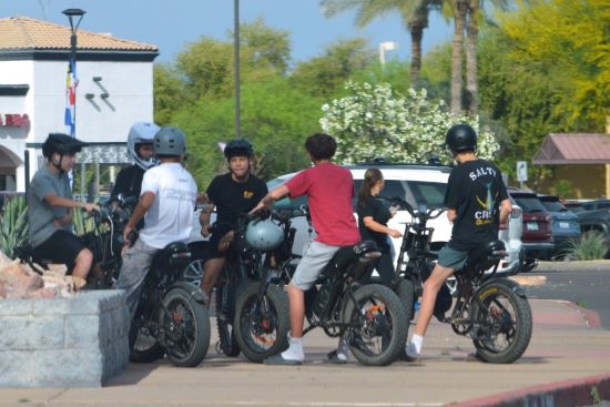 A group of teenagers gather with their e-bikes