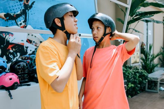 Two teenage boys strap on bicycle helmets