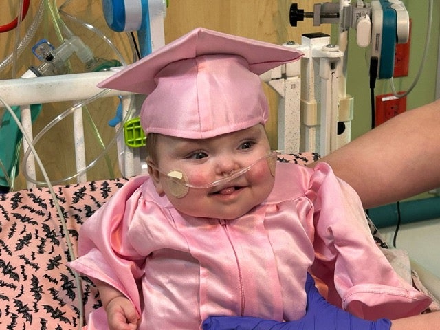 A baby in a pink graduation outfit